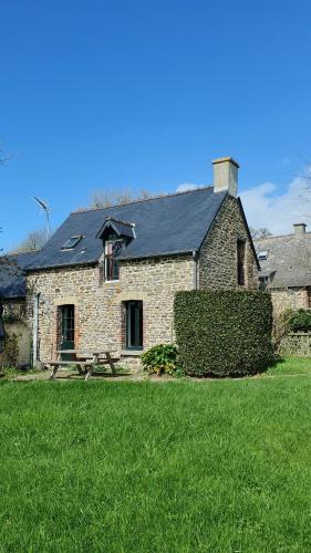 圣茹昂代盖雷特L'AUBERGE DE LA PORTE的草地上一座石头房子,屋顶黑色