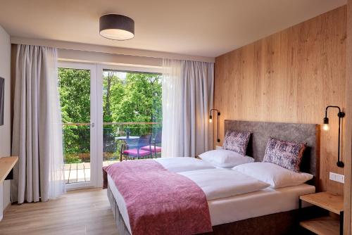 卡普伦HOTEL SONNBLICK Kaprun Salzburg - incl Zell am See-Kaprun Summercard的一间卧室设有一张大床和一个大窗户