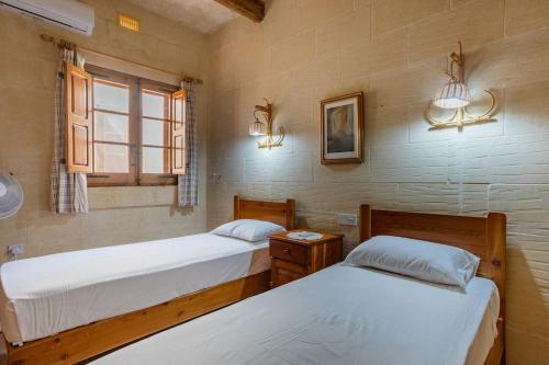 萨奈特Gozo Rustic Farmhouse with stunning views and swimming pool的一间卧室设有两张床和窗户。