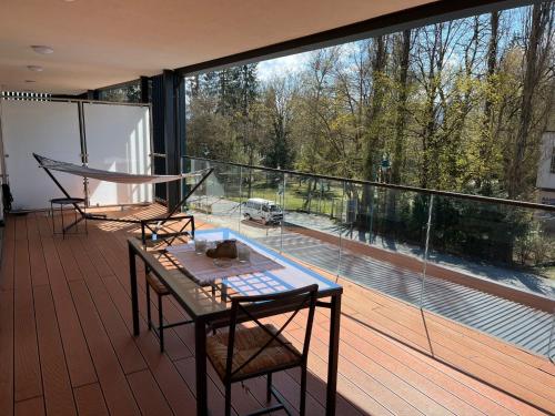 沃尔特湖畔佩莎赫Apartment Luxury Sunrise Appartement by Interhome的阳台配有桌椅和大窗户。