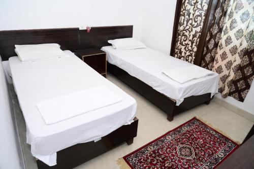 菩提伽耶Dwarka Home Stay的小房间设有两张床,铺着地毯