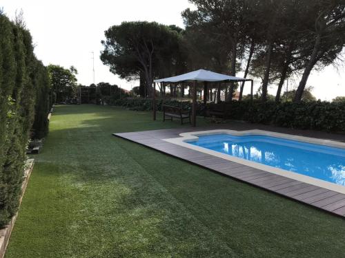滨海圣波尔Casa con piscina Sant Pol de Mar的庭院内的游泳池,配有桌子和遮阳伞