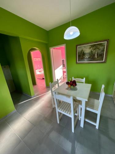 罗达Telis Apartments One的一间拥有绿色墙壁和白色桌椅的用餐室