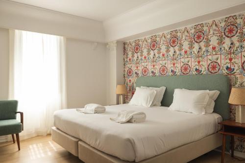 卡斯卡伊斯Pergola Boutique Hotel的一间卧室配有一张大床和两条毛巾