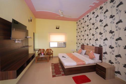 马图拉Hotel Mukund Priya- Near Krishna Janam Bhoomi的一间卧室配有一张床,并在一间客房内配有电视。