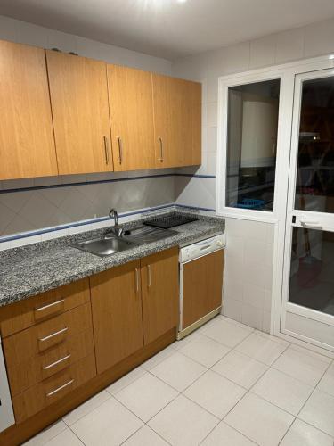 马拉加Luxurious Apartment 2 Bedroom 2 Bathroom Near Beach的厨房配有木制橱柜、水槽和窗户。