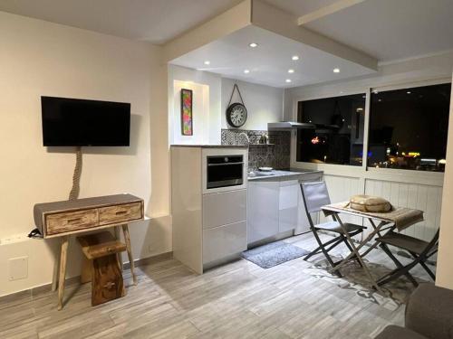 皮特尔角城C l e a n & N e w - cosy flat marina PAP Gosier的厨房配有电视和桌椅