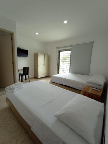 辛塞莱霍Hotel Palermo Sincelejo的一间卧室配有两张床、一张桌子和一把椅子