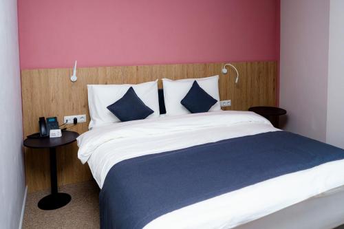 奇姆肯特Graf Hotel的一间卧室配有一张带蓝白色枕头的大床