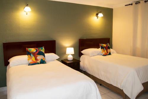 危地马拉Inari Hostal的配有2盏灯的酒店客房的2张床