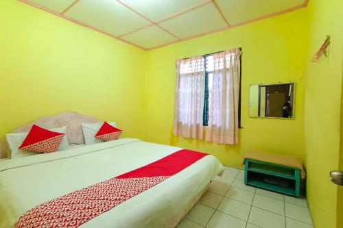 巴拉巴特OYO 92503 Penginapan & Villa Sirait的一间卧室配有红色和白色枕头的床