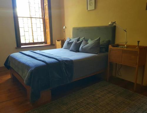 PortervilleThe Heritage country house的一间卧室配有一张带蓝色毯子的床和窗户。