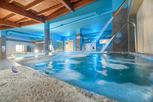 拉林Hotel Spa Norat Torre Do Deza 4* Superior的蓝色灯光的酒店的大型游泳池
