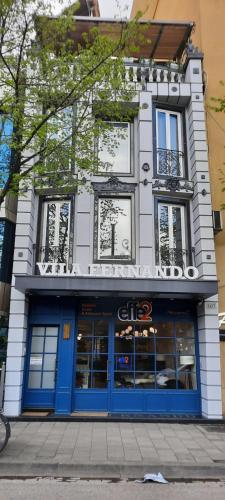 地拉那Hotel Villa Fernando Tirana的街道上设有蓝色门窗的建筑