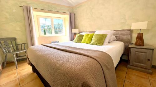 拉让提耶尔Logis Hôtel Restaurant Le Domaine de l'Eau Vive的一间卧室配有一张带绿色枕头的床和一扇窗户