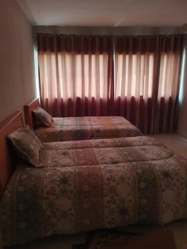斯法克斯Appartement confortable - Sfax centre的一间卧室设有两张床,窗户配有窗帘