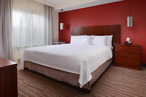 本殖民地Residence Inn by Marriott Dallas Plano The Colony的一间卧室设有一张红色墙壁的大床