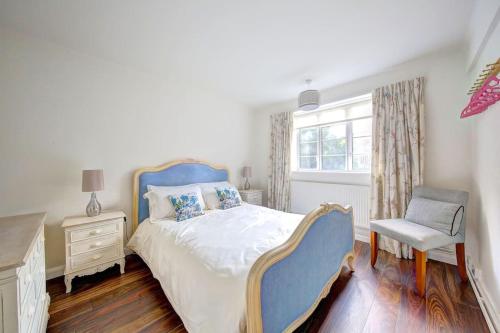 泰丁敦2 bed flat - SW London with parking的卧室配有床、椅子和窗户。