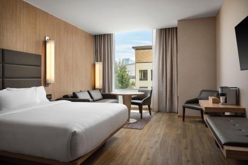 弗赖拉辛AC Hotel by Marriott Dallas Frisco的酒店客房带一张床、一张桌子和椅子