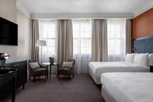 布里斯托布里斯托万豪皇家酒店的酒店客房带两张床和一张桌子以及椅子。
