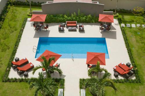 TocumenCourtyard by Marriott Panama Metromall的享有带桌子和遮阳伞的游泳池的顶部景致