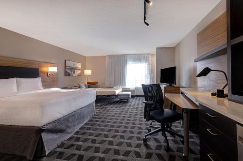 门罗TownePlace Suites by Marriott Monroe的酒店客房设有一张大床和一张书桌。