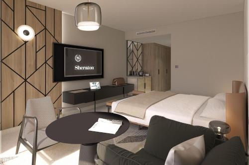 梅里尼亚克Sheraton Bordeaux Airport的一间卧室配有一张床、一张桌子和一台电视。