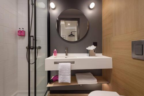 里斯本Moxy Lisboa Oriente的浴室配有盥洗盆和带镜子的淋浴