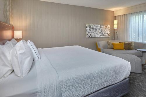 斯普林菲尔德尤金斯普林菲尔德万怡酒店的酒店客房设有一张白色大床和椅子