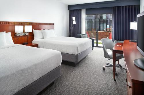 罗利Courtyard by Marriott Raleigh Midtown的酒店客房配有两张床和一张书桌