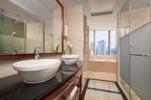 南宁南宁鑫伟万豪酒店的浴室配有2个盥洗盆、浴缸和淋浴。