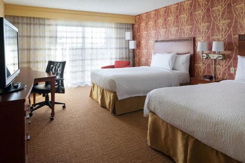 圣安娜梅萨海岸南海岸新城万怡酒店的酒店客房设有两张床、一张桌子和一台电视。