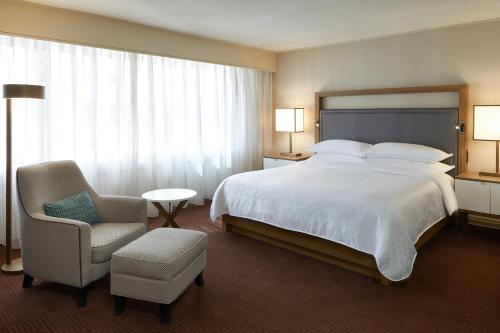 渥太华渥太华喜来登酒店的酒店客房带一张大床和一把椅子