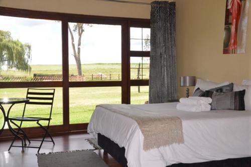 塞昆达ThakhuBrunfelsia的一间卧室配有一张床、一张桌子和一个大窗户
