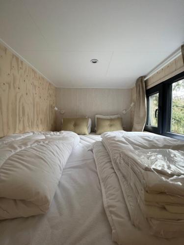 宁斯佩特Ultiem ontspannen in compleet ingericht tiny house in bosrijke omgeving的一张大白床,坐在房间里