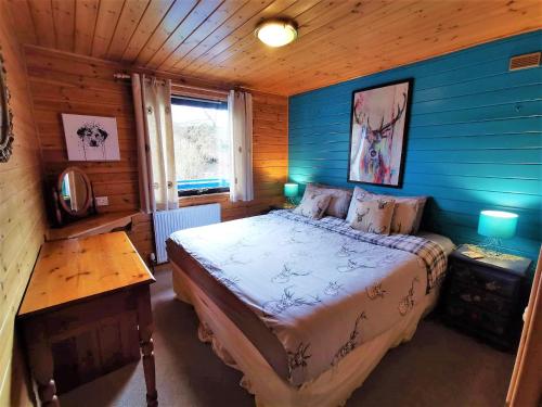新卡姆诺克Glen Bay - 2 Bed Lodge on Friendly Farm Stay with Private Hot Tub的一间卧室设有一张床和木墙