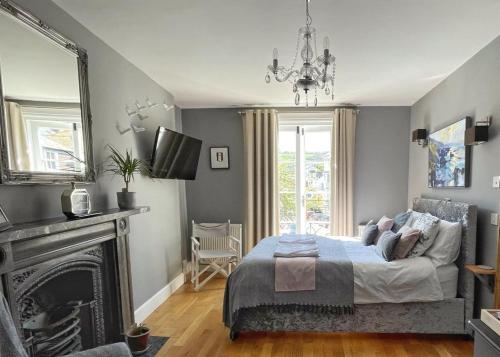 达特茅斯Millpool House的一间卧室配有一张床、一个壁炉和一个吊灯。