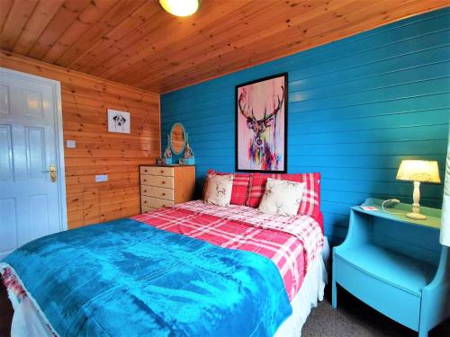 新卡姆诺克Glen Roe - 3 Bed Lodge on Friendly Farm Stay with Private Hot Tub的蓝色卧室,配有床和蓝椅