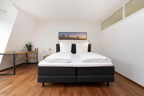 弗莱堡Bike- und Ferienhotel Freiburg的一间卧室配有一张带白色床单的床和一张书桌。