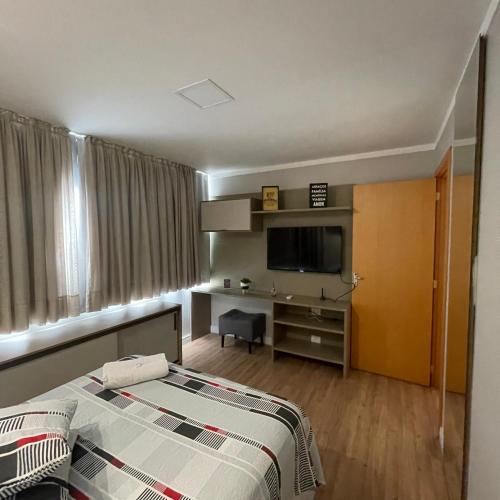 本图贡萨尔维斯Apartamento Elegante e aconchegante na Serra Gaúcha #的一间卧室配有一张床和一张书桌及电视