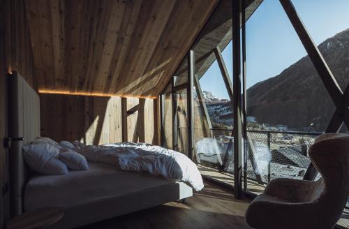 安泰塞尔瓦·迪·梅佐Amus Chalets Dolomites - Luxury Chalets South Tyrol的一间卧室设有一张床和一个大窗户