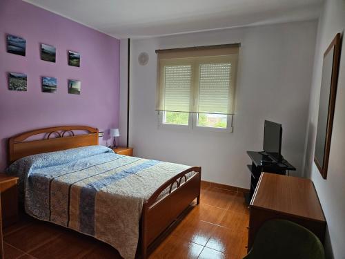拉赫Apartamento en Laxe, Costa da Morte的一间卧室配有一张床、一张书桌和一台电视