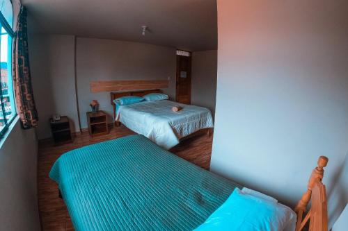 瓦拉斯Chacraraju Hostel的一间卧室设有两张床和窗户。