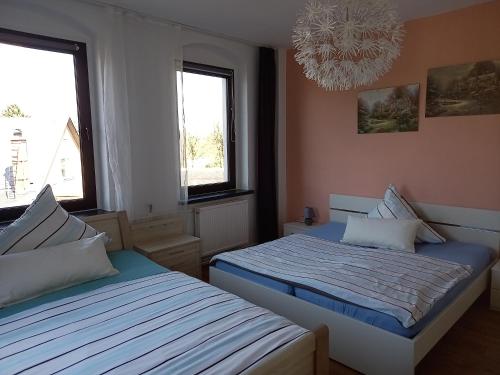 施内贝格Familienfreundliche Ferienwohnung Erzgebirge的一间卧室配有两张床、一个吊灯和两个窗户。