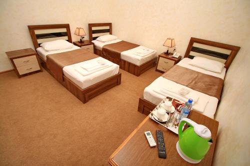 第比利斯villa old sololaki的酒店客房设有三张床和一张带遥控器的桌子。