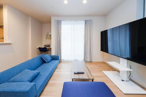 东京Higashi Komagata House的客厅配有蓝色的沙发和平面电视。