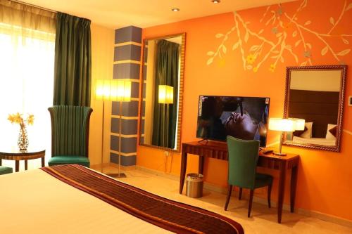 迪拜艾尔马纳尔公寓大酒店的一间卧室配有一张床、一张书桌和一面镜子