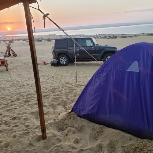 ‘Izbat Būrīsh al GharbīyāhSamuel Dunes的海滩上的蓝色帐篷和卡车