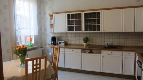 BergfeldFerienwohnung am Drömling Südheide - Gerda的厨房配有白色橱柜、桌子和水槽。