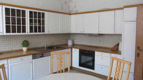 BergfeldFerienwohnung am Drömling Südheide - Gerda的白色的厨房配有白色橱柜和水槽